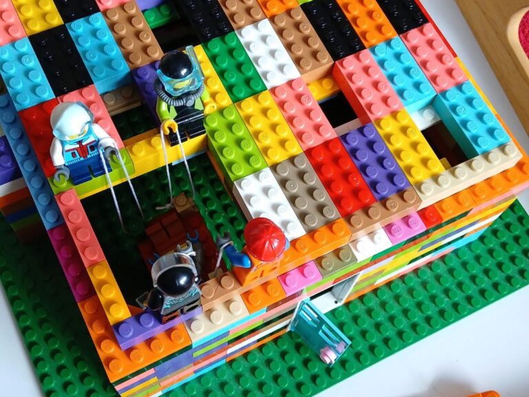 A lego model showing lego figures lowering a figure through the roof of a lego house