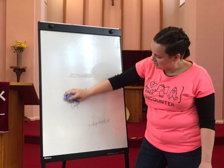A woman rubbing words off a whiteboard.