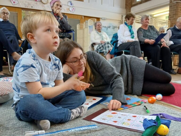 A small boy and his mum listening to the talk and playing bingo.