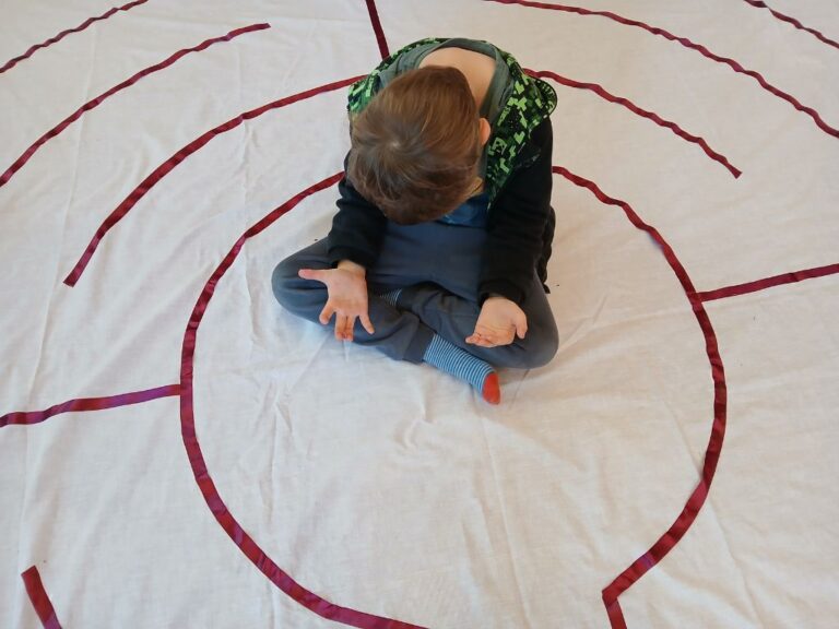 A young boy sat praying in the centre of a labyrinth.