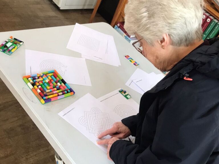 A lady using her finger to trace a labyrinth on a piece of paper.