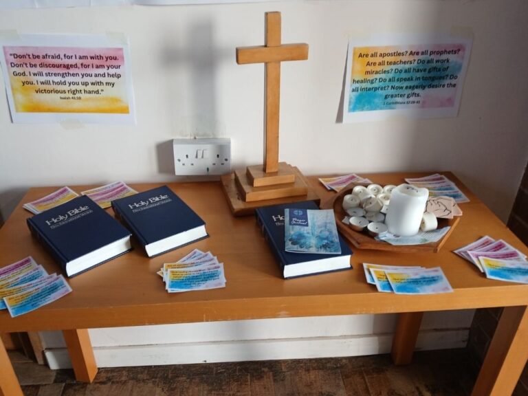 A table in the prayer corner with bibles, a cross and printed bible verses about calling.